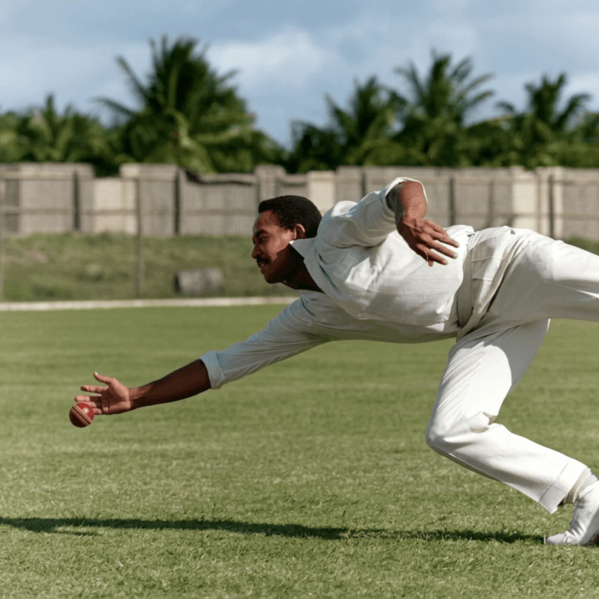 Sir Garry Sobers diving low to field a cricket ball.